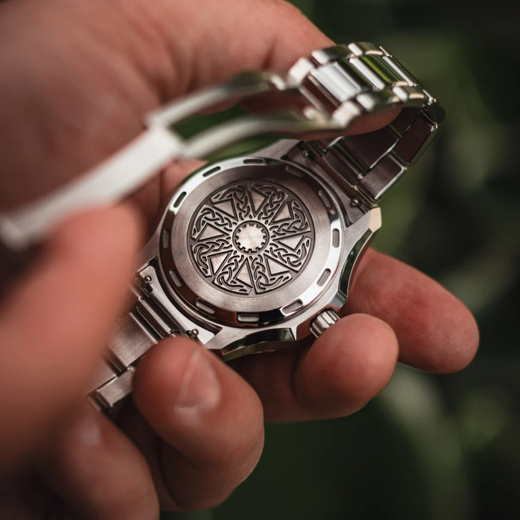 Veles caseback engraved with the kolovrat, held in the hand