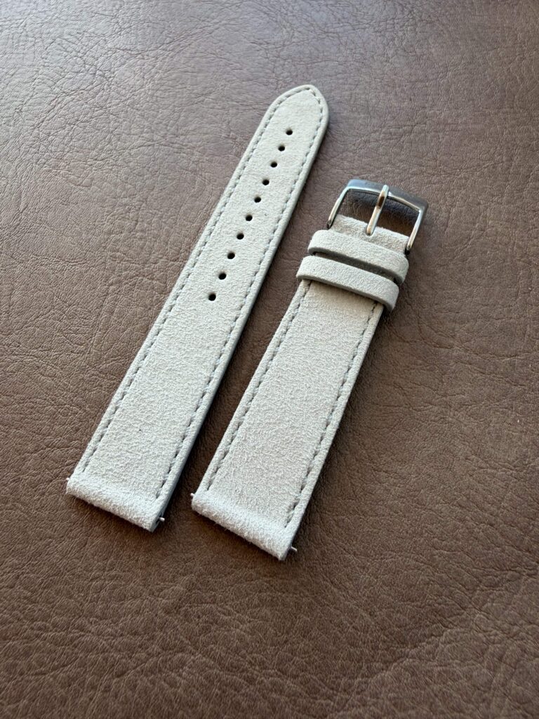 Light grey suede strap on a leather backdrop