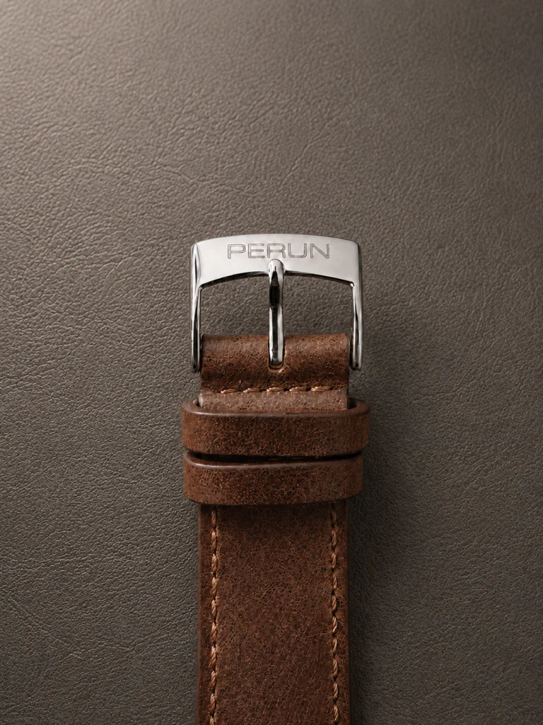 Polished steel buckle engraved PERUN, on a brown leather strap
