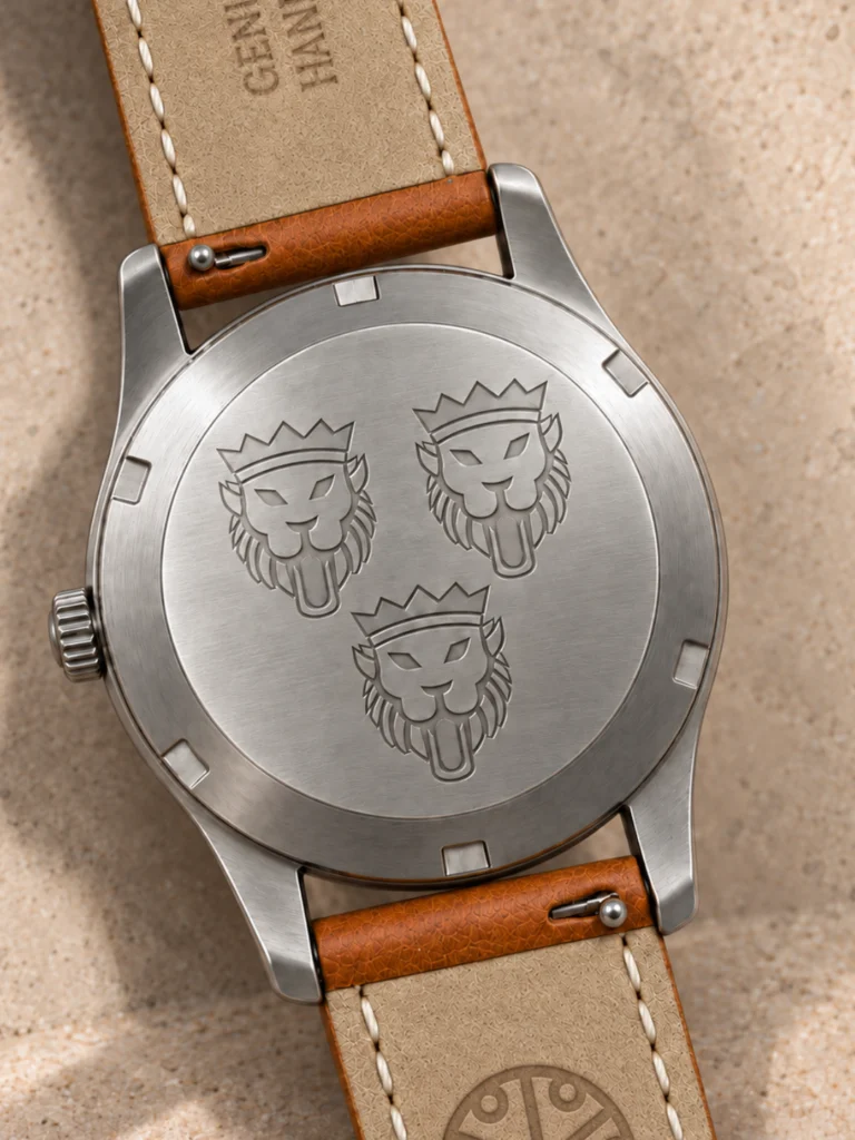Solid steel Knez caseback engraved with three crowned lions, on a cognac leather strap.